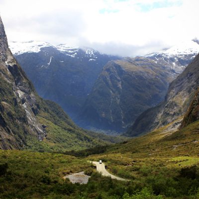 A van driving through a mountain pass on the way to Milford Sound